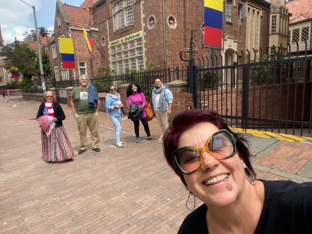 A imagem mostra os intercambistas passeando e conhecendo a cidade com um prédio com a bandeira da Colômbia (cores: amarelo, azul e vermelho)